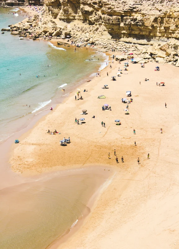 Beachgoers beneath sandstone cliffs